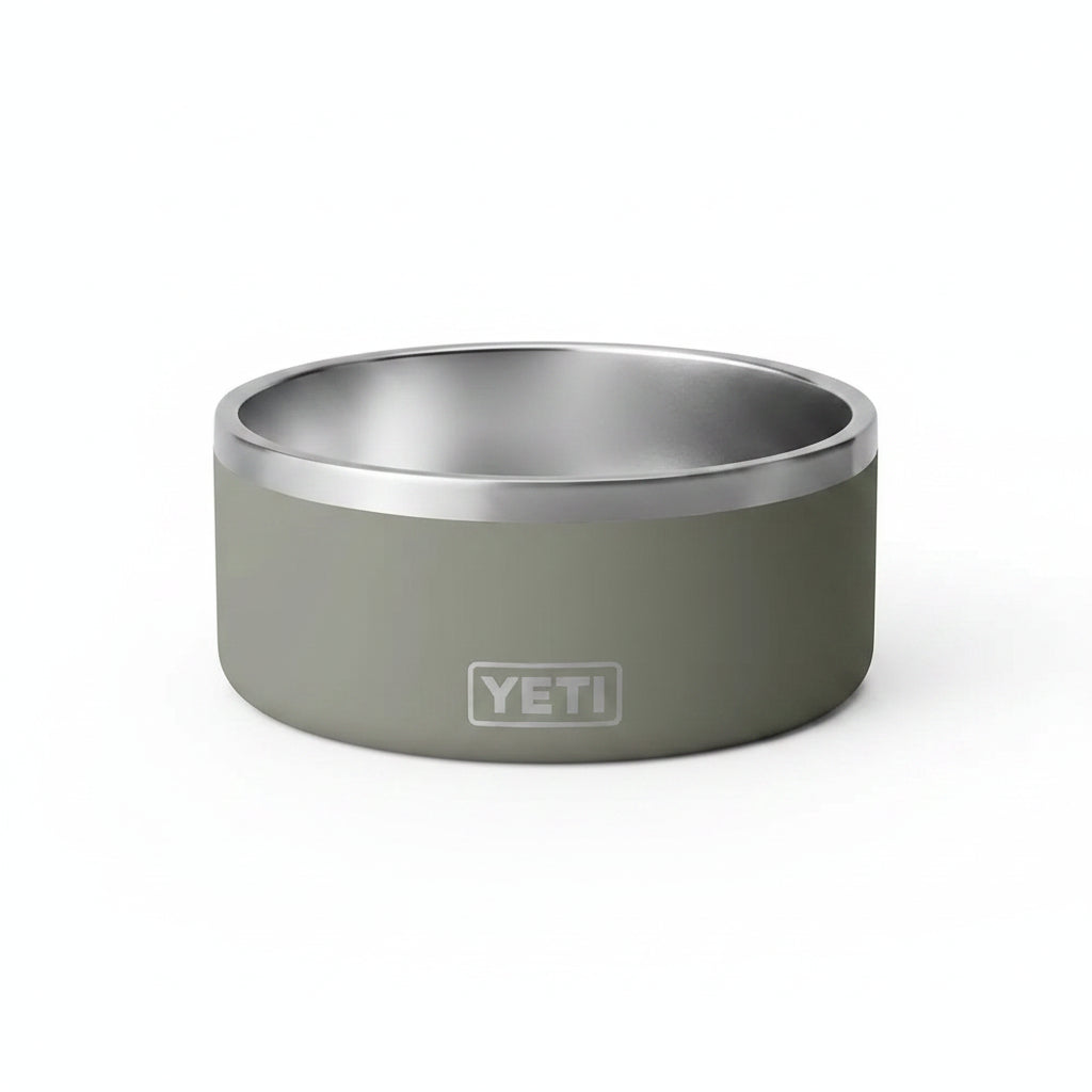 A YETI pet bowl with a matte sage green exterior and a brushed stainless steel interior, featuring the embossed YETI logo on the front.